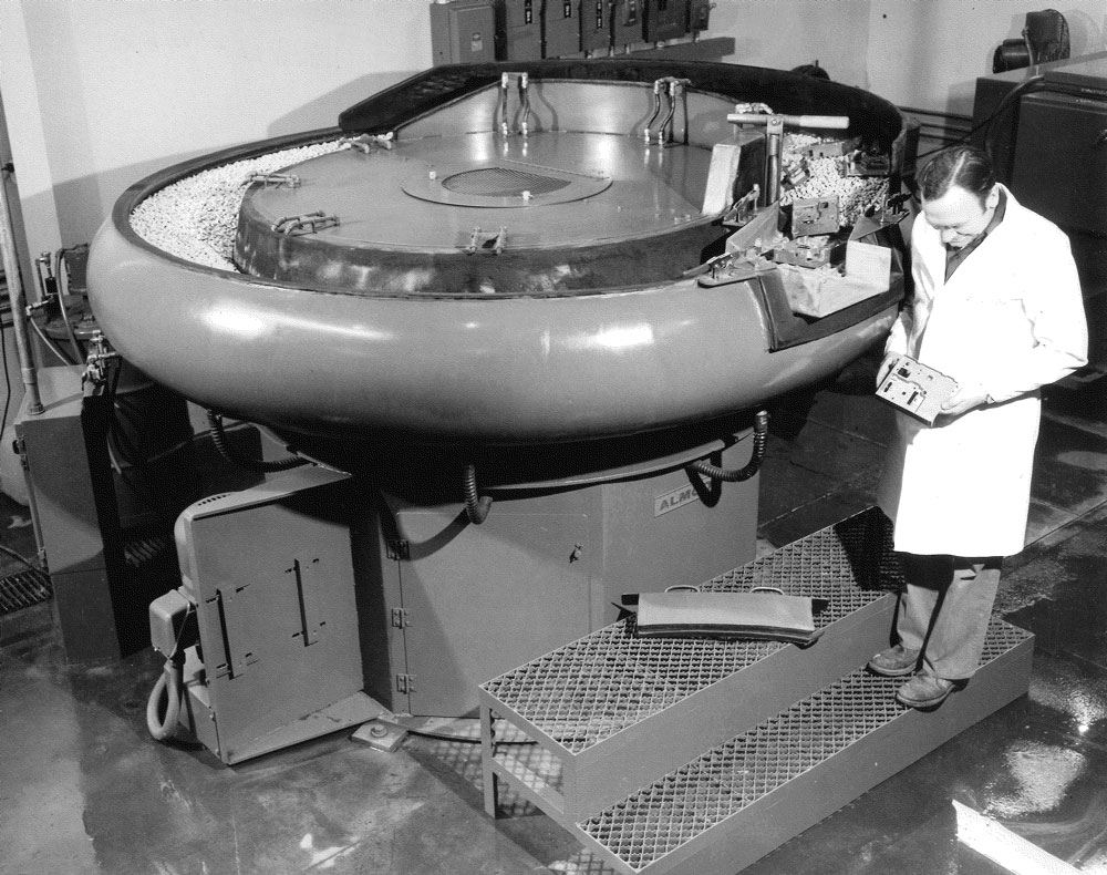 Operator examines finished part from a large vibratory bowl